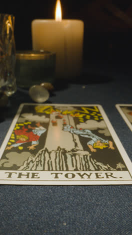 Vertical-Video-Close-Up-Shot-Of-Person-Giving-Tarot-Card-Reading-Laying-Down-The-Tower-Card-On-Table